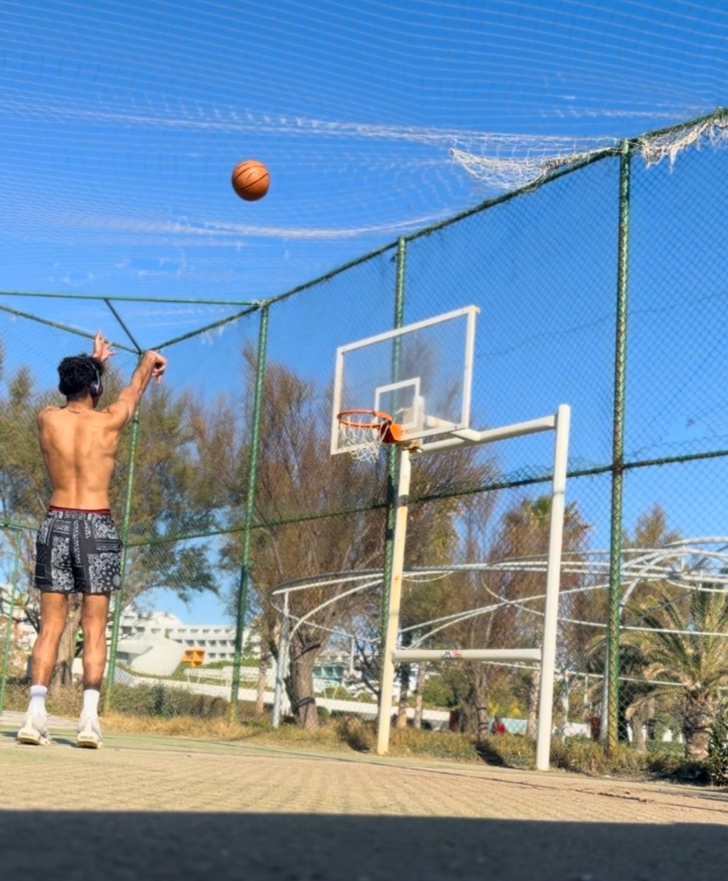 Jeeve taking a basketball shot on an outdoor court