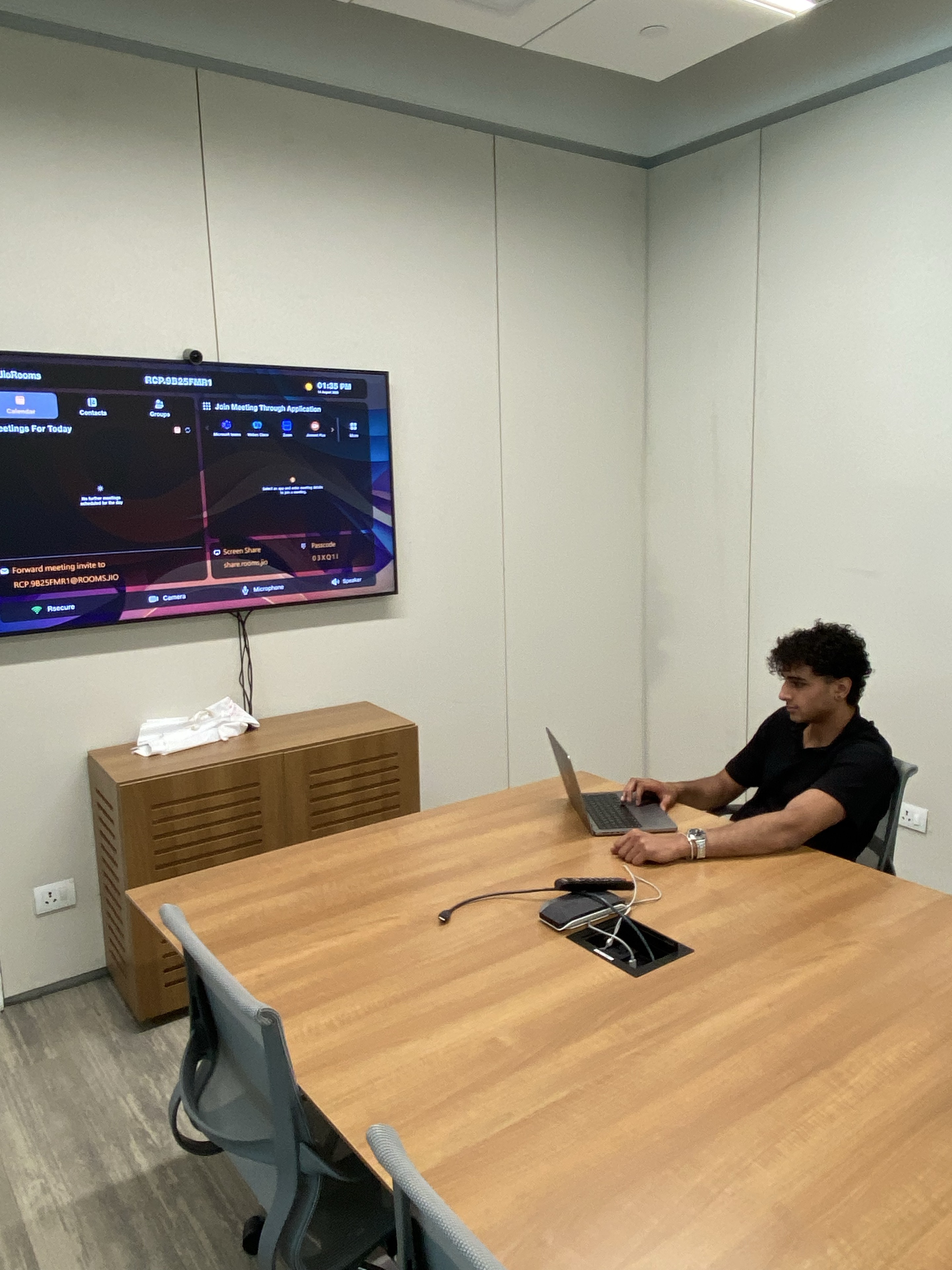 Jeeve working on a laptop in a meeting room during an internship
